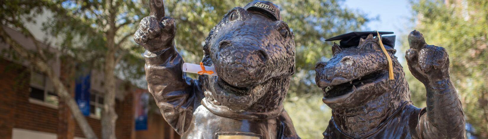 Metal statues of Albert and Ablerta Gator wearing graduation caps.