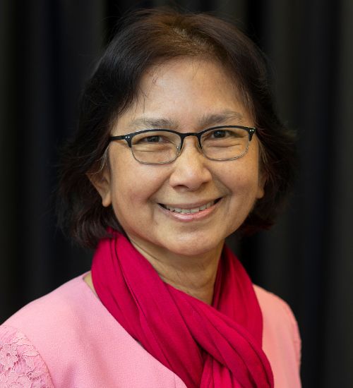 Dr. Amy Simonne Smiles in front of a dark gray backdrop.