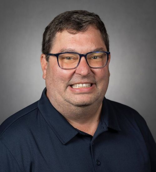 Dr. Pracht smiles in front of a gray backdrop.