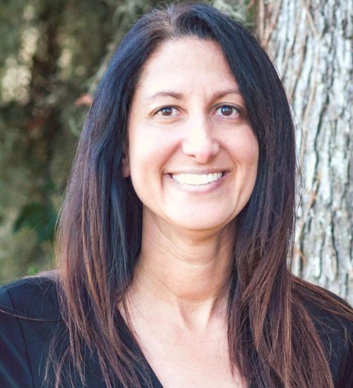 Dr. Radunovich smiles in front of a tree.