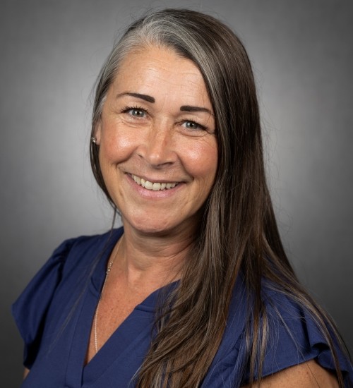 Kate Fletcher smiles in front of a gray backdrop.