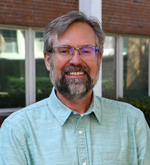 Dr. Forthun smiles in front of a university building.