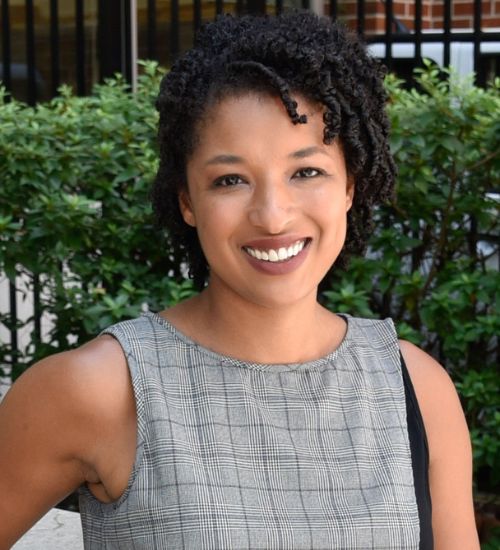 Dr. Vilaro smiles in front of a bush.
